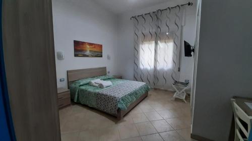 a small bedroom with a bed and a window at Pratza Froria in Villasimius