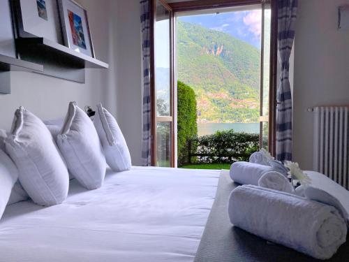 a white bed with pillows and a view of a mountain at Regina di Laglio - Free Parking, Garden, Lake View in Laglio