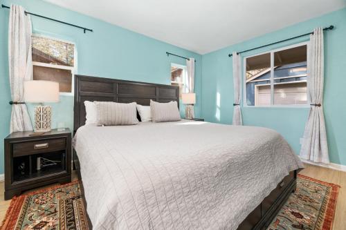 a blue bedroom with a large bed and two windows at Casa de Campo - Beautiful mountain home equipped with everything you need for a relaxing getaway! in Big Bear City
