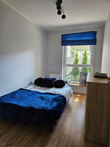 a bedroom with a bed with blue sheets and a window at Nadmorski apartament premium in Gdynia