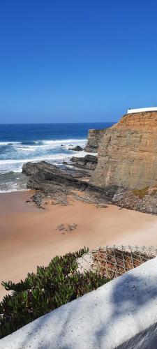 a sandy beach with rocks and the ocean at Casa Esmar in Odemira