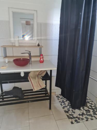 uma casa de banho com um lavatório e uma cortina de chuveiro em Maisonnette sur les hauteurs de la Baie des mulets Vauclin em Le Vauclin