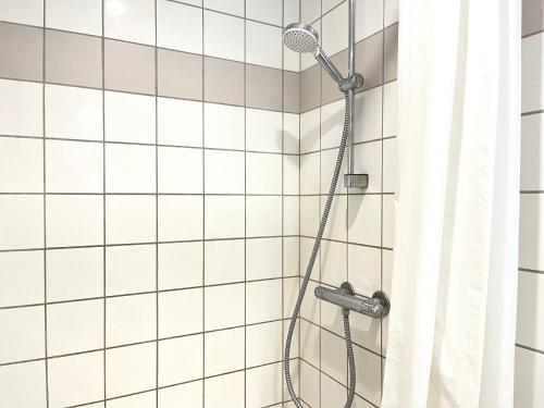 a shower with a shower head in a white tiled bathroom at Newly Renovated Apartment With 1 Bedroom In Kolding in Kolding