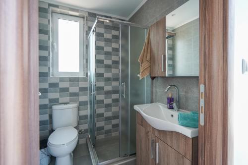 a bathroom with a toilet and a sink and a shower at Sunshine House Kos - Easy living by the sea in Kefalos