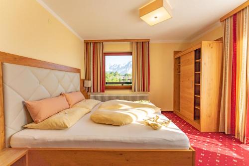 a bedroom with a large white bed with a window at Hotel Garni Hochwurzen in Schladming