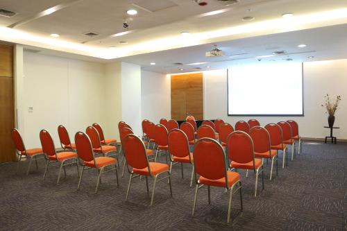 a conference room with orange chairs and a screen at Wyndham Concepcion Pettra in Concepción