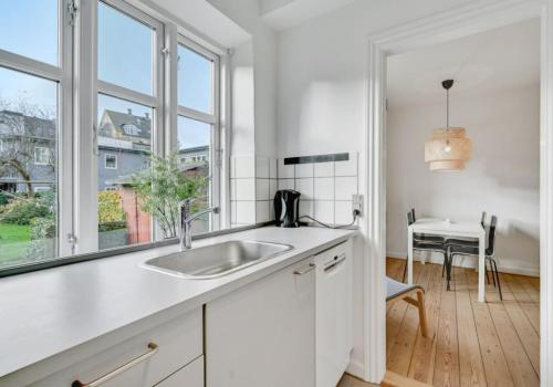 une cuisine blanche avec un évier et une fenêtre dans l'établissement Two Bedroom Apartment In Aarhus, Ole Rmers Gade 104, à Aarhus