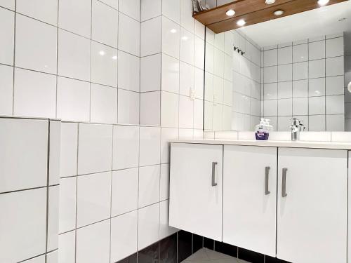 a white tiled bathroom with white cabinets and a sink at Nice Apartment Located Near Vesterbro in Aalborg