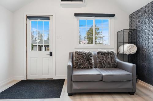a living room with a gray couch and windows at Luxe Lodges on Lake Erie in Port Dover