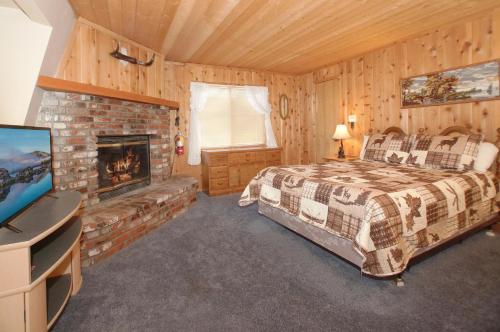 Un dormitorio con una cama y una chimenea. en Mountain Bliss - Semi-secluded woodsy quiet cabinm, covered deck with a porch swing!, en Big Bear City