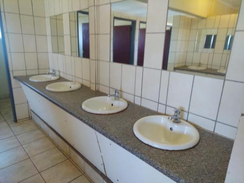 three sinks in a public bathroom with mirrors at KUNGWINI CENTER in Bronkhorstspruit