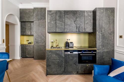 een keuken met grijze marmeren muren en blauwe stoelen bij Luxury 2 Bedroom 1 Bathroom - Louvre Museum & Opera in Parijs