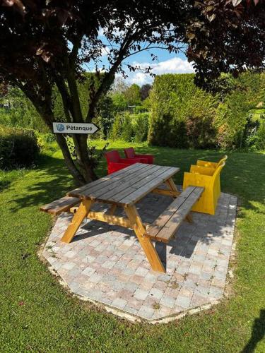 a wooden picnic table and chairs in a yard at La maison Girafe in Faverolles