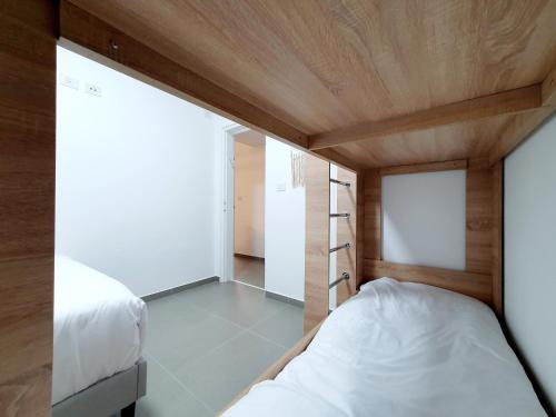 ein kleines Schlafzimmer mit weißem Bett und Holzdecke in der Unterkunft Acrey 