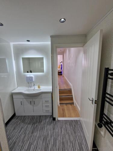 a white bathroom with a sink and a hallway at Balco Plaza Studio in Nottingham