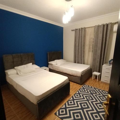 een slaapkamer met 2 bedden en een blauwe muur bij Eastern Nights in Caïro