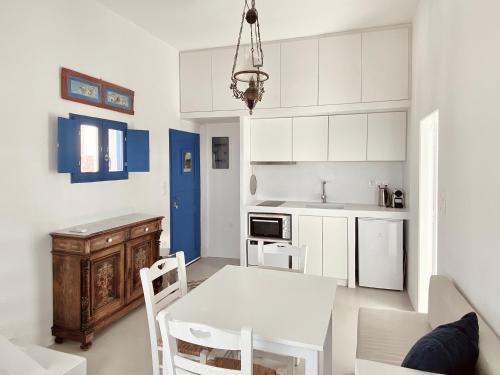 Sunset Pyrgos في بيرغوس: مطبخ بدولاب بيضاء وطاولة وكراسي بيضاء
