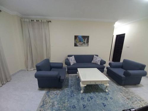 ein Wohnzimmer mit blauen Sofas und einem Couchtisch in der Unterkunft Relaxing Apartment with garden view in New Cairo in Kairo