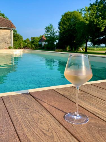 a glass of wine sitting on a table next to a swimming pool at Le Poutic gîte et maison d'hôtes in Créon-dʼArmagnac