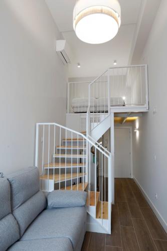 a living room with a couch and a spiral staircase at Pension Mendi Azpi Rooms in Mutriku