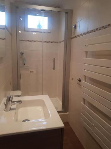 une salle de bain blanche avec un lavabo et une douche dans l'établissement Maison Bateau, à Lion-sur-Mer