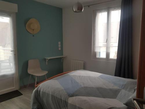 um quarto com uma cama, uma cadeira e janelas em Maison Bateau em Lion-sur-Mer