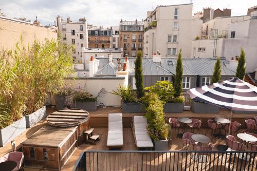 a rooftop patio with tables chairs and an umbrella at Hôtel Wallace - Orso Hotels in Paris