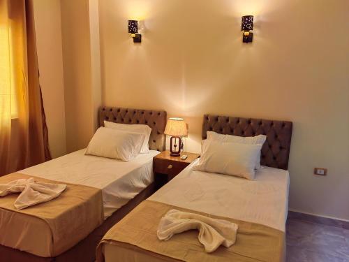 a room with two beds and a lamp on a table at Gem Overlooking inn in Cairo