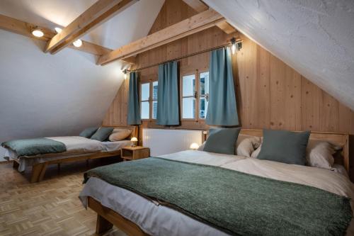 two beds in a room with wooden walls and blue curtains at Chalupa Bocza in Nižná Boca