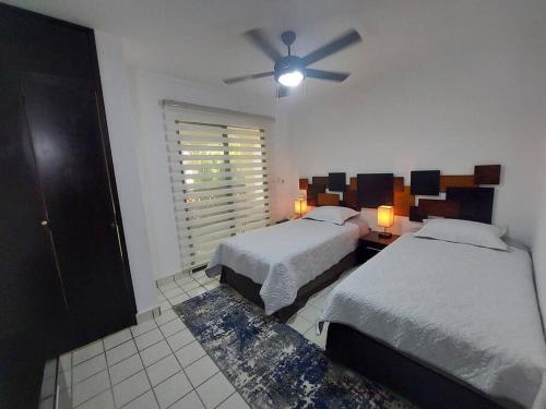 Un dormitorio con dos camas y un ventilador de techo. en Villas Cozumel #9, en Cozumel