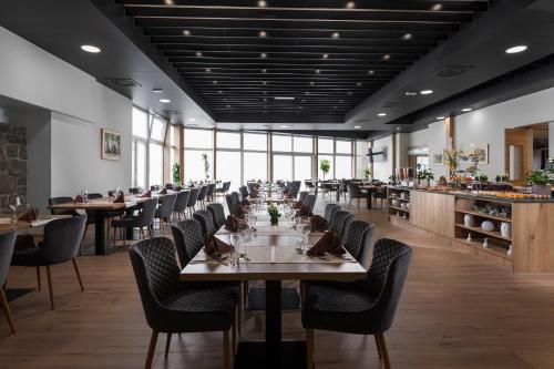 un comedor con mesas, sillas y ventanas en Grand Hotel BELLEVUE, en Hočko Pohorje