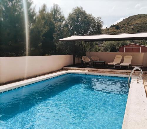una piscina con mesa y sillas junto a un edificio en El Marqués, magnífica casa rural con piscina, en Almería