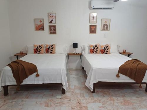 two beds in a room with white walls at Casa Las Palmas in Cancún