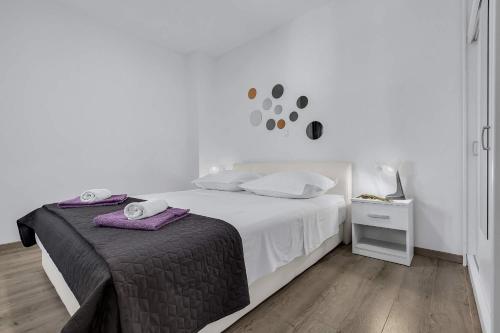 a white bedroom with a bed and a night stand at Sunny Garden Apartments Ana in Makarska