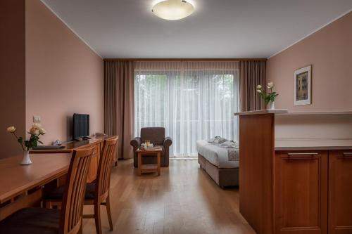 ein Wohnzimmer mit einem Schreibtisch und ein Zimmer mit einem Bett in der Unterkunft Grand Hotel BELLEVUE in Hočko Pohorje