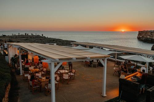 a restaurant on the beach with a sunset in the background at VORAMAR in Cala en Forcat