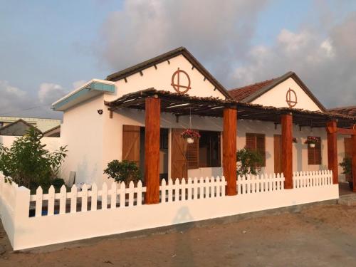 a white house with a white picket fence at Blue Sea Homestay 2 in Phu Yen