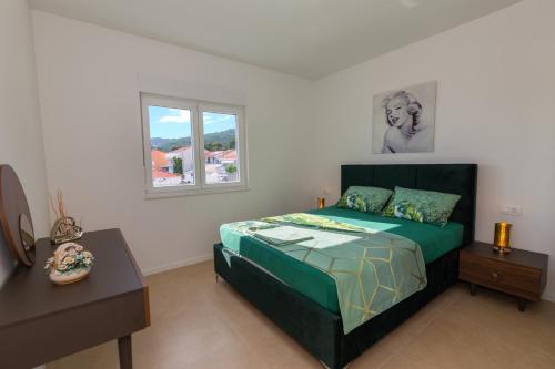 Schlafzimmer mit einem Bett, einem Fenster und einem Tisch in der Unterkunft Apartman SMARAGD Živogošće in Živogošće