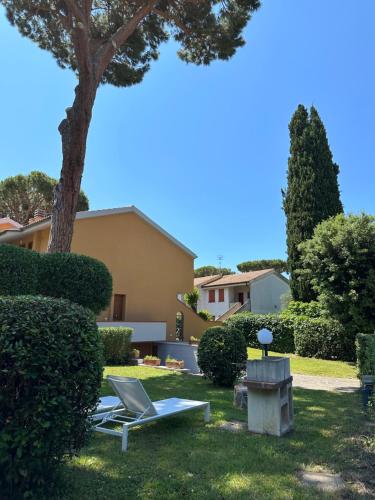 un patio con 2 tumbonas y un árbol en Appartamenti Portiglioni-Cipressi, en Puntone di Scarlino