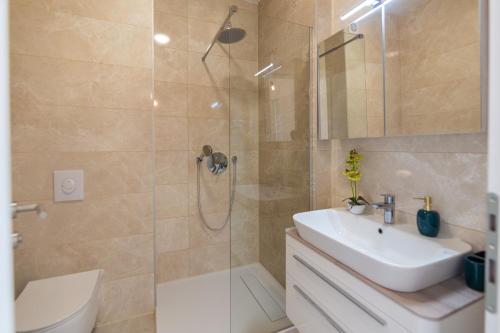 La salle de bains est pourvue d'une douche, d'un lavabo et de toilettes. dans l'établissement Apartman SMARAGD, à Živogošće