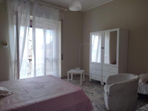 una camera da letto con un letto, un comò e una sedia di Don Aurelio in città ad Acireale
