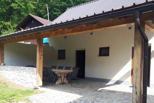 einem Holzpavillon mit einem Tisch vor einem Haus in der Unterkunft Posestvo Tmžek in Bovec