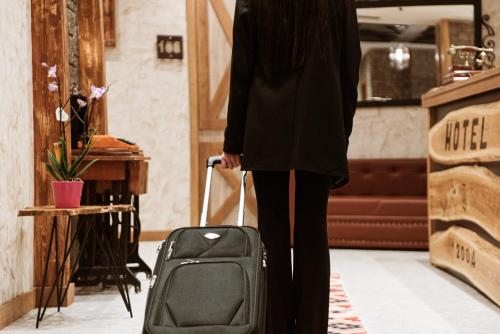 a woman is pulling a suitcase in a room at Hotel Taverna Devolli in Kuçovë