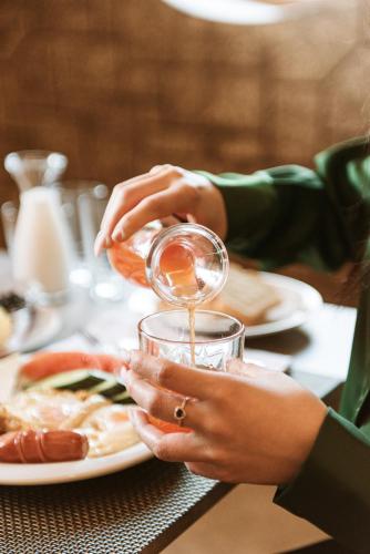 a woman pouring wine into a glass at a table at Hotel Taverna Devolli in Kuçovë
