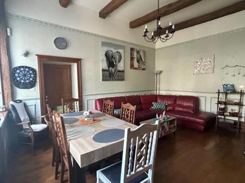 un salon avec une table et un canapé rouge dans l'établissement Chambres d'hôtes dans une maison de caractère, à Mussey-sur-Marne