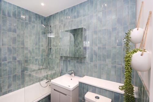 a blue tiled bathroom with a sink and a toilet at The London Secret, 1 bed flat with patio - Zone 2 in London