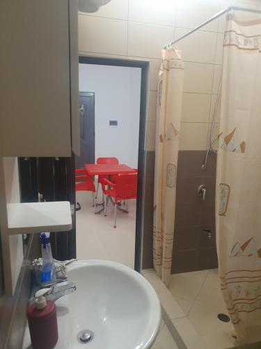 uma casa de banho com um lavatório e um quarto com uma mesa em Gruda Apartments em Shkodër