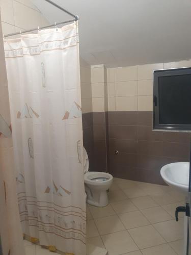 a bathroom with a toilet and a shower curtain at Gruda Apartments in Shkodër
