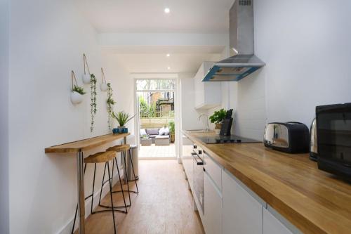 a kitchen with white cabinets and a wooden counter top at The London Secret, 1 bed flat with patio - Zone 2 in London