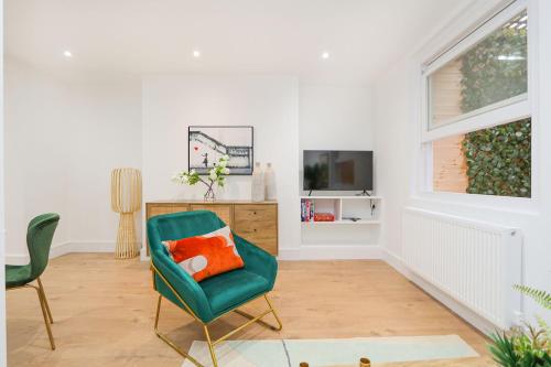 a living room with a green chair and a television at The London Secret, 1 bed flat with patio - Zone 2 in London